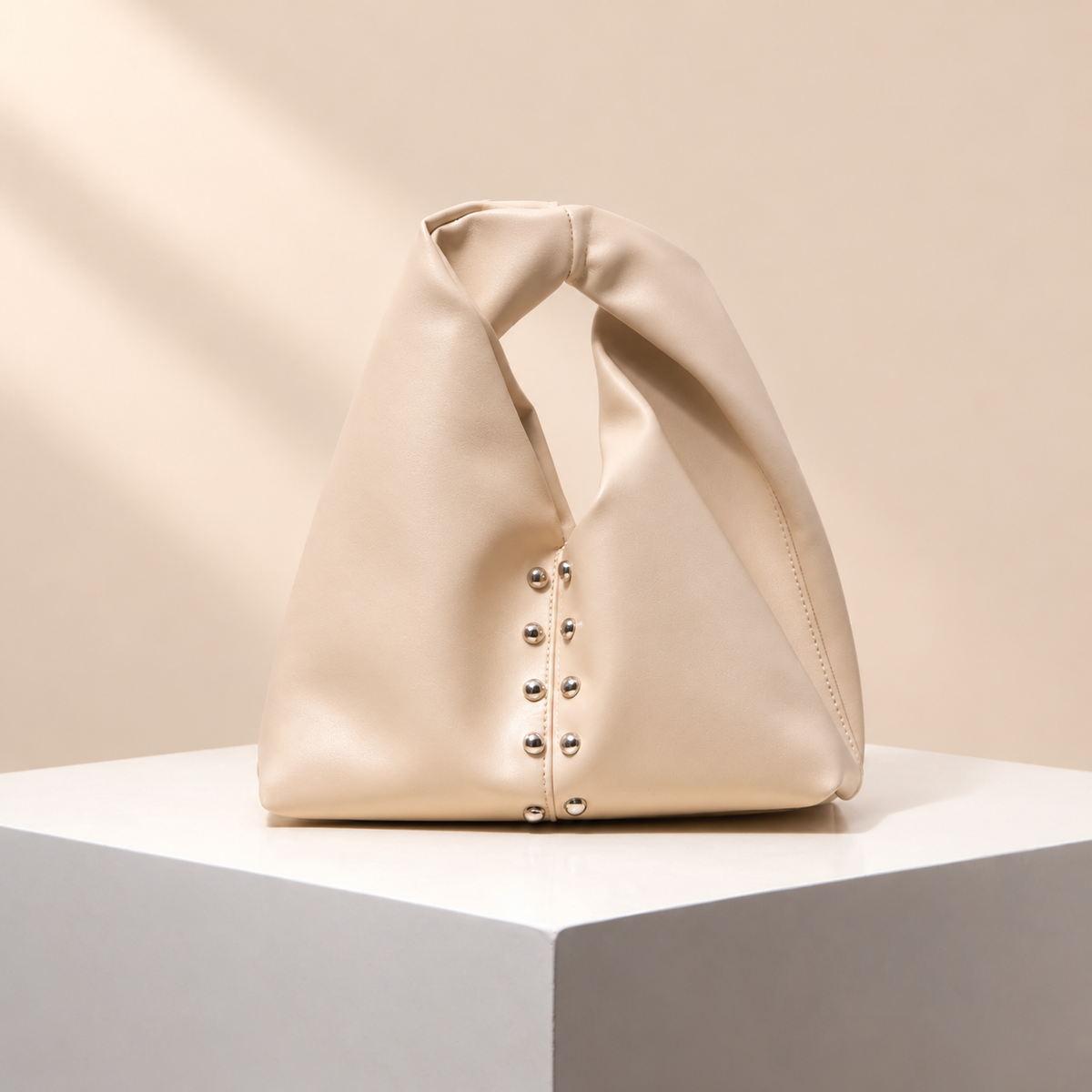 Avelune Knotted Handle Bag — warm beige studio background