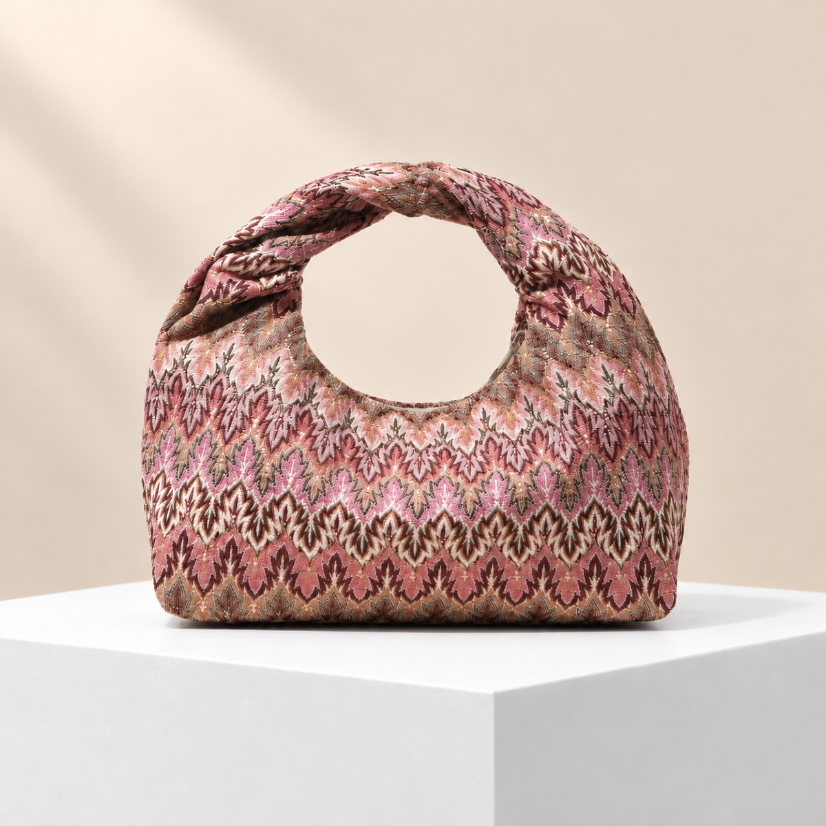 Virelia Patterned Top Handle Bag — white plinth, warm beige background