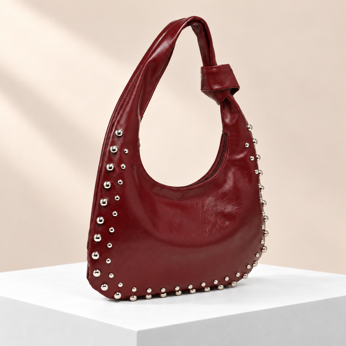 Velloria Studded Hobo Bag — white plinth, warm beige background