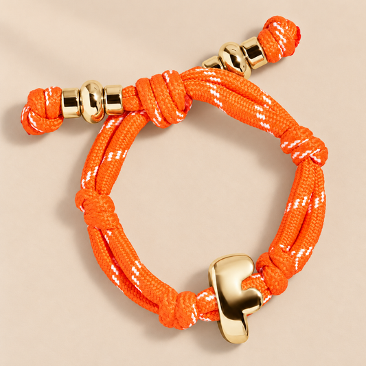 MiraWeave Colourful Woven Letter Bracelet — warm beige studio background