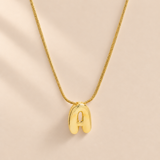 Aloura Bubble Initial Pendant Necklace — warm beige studio background
