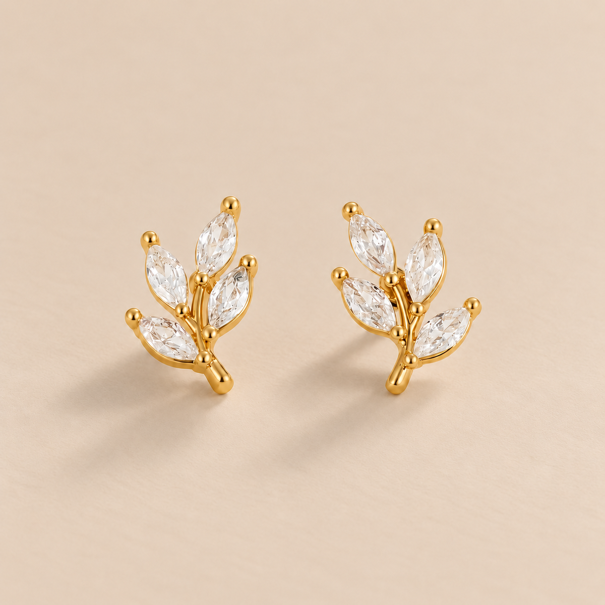 Crystal Leaf Stud Earrings — warm beige studio background