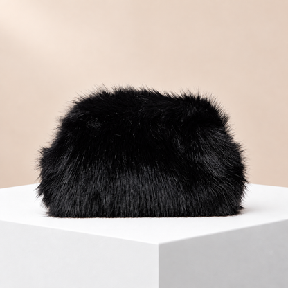 Noélie Black Faux Fur Clutch — white plinth, warm beige background