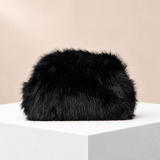 Noélie Black Faux Fur Clutch — white plinth, warm beige background