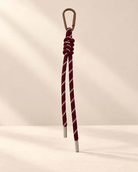 Knotelle brown patterned rope bag charm with silver tips on warm ivory background